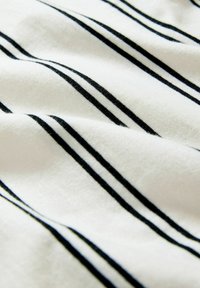 Katoenen stof met een zachte textuur, voorzien van horizontale zwarte strepen op een witte achtergrond. De strepen zijn gelijkmatig verdeeld en stevig van kleur.