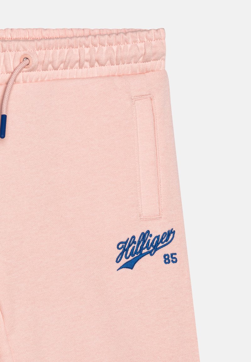 Jasnoróżowe spodnie dresowe, wykonane z bawełny, z elastycznym pasem, niebieskim haftowanym logiem "Hilfiger 85" oraz kieszeniami bocznymi.