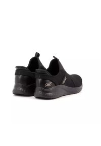 Sneakers neri slip-on con un upper in tessuto morbido, suola testurizzata e un accento con logo sul lato. Progettate per comfort e facilità d'uso.