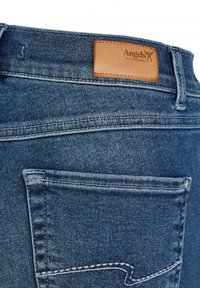 Donkerblauwe denim jeans met een gladde textuur, leren patch met het label "Angels" en opvallende stikdetails. Beschikt over een achterzak.