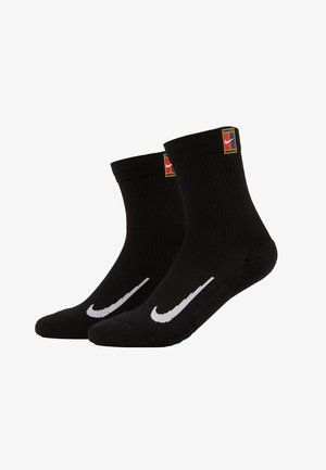 Czarne skarpetki bawełniane do kostek z prążkowanym wzorem, białym logo Nike w kształcie łuku oraz kolorową metką z logo blisko mankietu.