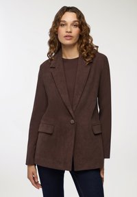 Brązowa marynarka z korduroy o wyraźnych klapach, z zapięciem na jeden guzik i dwoma przednimi kieszeniami, charakteryzująca się miękką teksturą w dopasowanym fasonie.