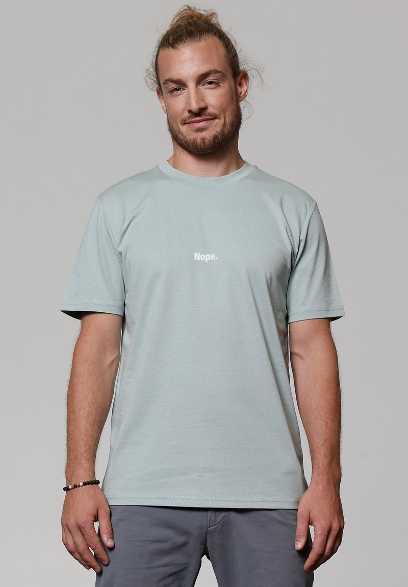 Lichtblauw katoenen T-shirt met korte mouwen, voorzien van de tekst "Nope." in het wit. Eenvoudig ontwerp, ronde halslijn, ontspannen pasvorm.