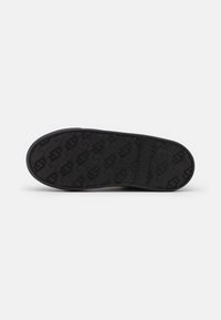 Suola di scarpa nera con una superficie testurizzata caratterizzata da modelli logo intrecciati. I bordi lisci e il tacco arrotondato offrono un design uniforme.