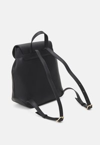 Czarny skórzany plecak o wyraźnej formie, z górnym uchwytem, regulowanymi paskami i akcentami z złotego metalu. Teksturowana powierzchnia.