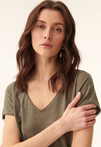 Olivengrøn, kortærmet V-hals t-shirt i blødt stof med en afslappet pasform og diskrete stikninger langs halsudskæringen og ærmerne.