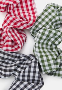 Quatro scrunchies de tecido em padrões xadrez vermelho, verde, preto e branco, apresentando uma textura suave e um design franzido.