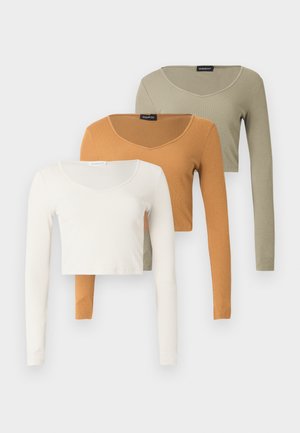 Three long-sleeve cropped ribbed tops in cream, mustard, and olive green with scoop necklines, displayed layered against a white background.