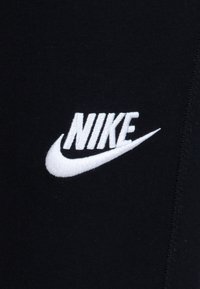 Black cotton fabric with white embroidered "NIKE" logo and swoosh design. Smooth texture with tight stitching along the edges.