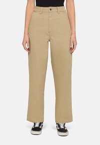 Beige wijde broek met een hoge taille, voorzien van voorzakken en een knoopsluiting, gecombineerd met zwarte sneakers.