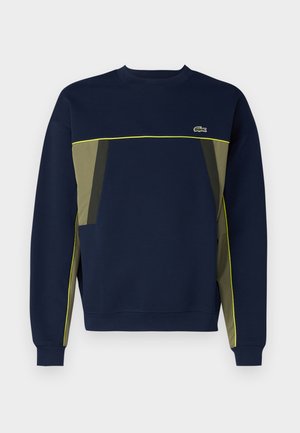 Navy sweatshirt with green and gray panel accents, featuring a round neckline and yellow piping. Lacoste logo on the upper left chest.