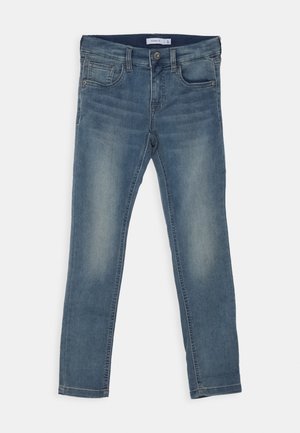 Tynne jeans i blå denim med frontlukking med knapp, fem lommer og subtil fading langs lårene og knærne.