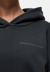 Felpa nera con superficie testurizzata, che presenta un logo "GOODFORNOTHING" in una progettazione leggermente sollevata sul petto.