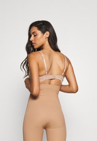 Naaktkleurig body met een zachte textuur en verstelbare spaghettibandjes, voorzien van een rug met kantafwerking. Subtiele kleuren die met de huidtoon versmelten.