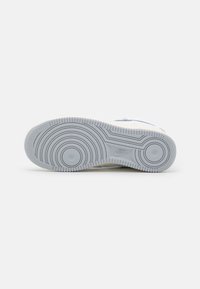 White sneaker sole featuring a circular pattern, textured rubber material, with raised edges and a Nike logo embossed near the center.