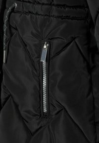Chaqueta acolchada negra con un bolsillo con cremallera, textura de rombos y cordón ajustable. Detalle del hardware de la cremallera metálica visible.