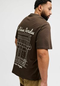 Brown cotton T-shirt featuring a white graphic of a storefront on the back, with the text "Au Rêve Perdu" above and "do to forget" below.