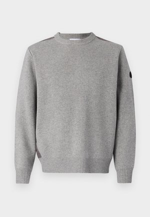 Grå strikket sweater med ribbete tekstur, rund hals og kontrasterende accenter ved skuldrene. Ærmerne er også ribbet.