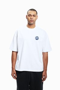 T-shirt branca de algodão com mangas curtas, decote arredondado e um desenho gráfico circular azul com a palavra "FAVELA" no peito.