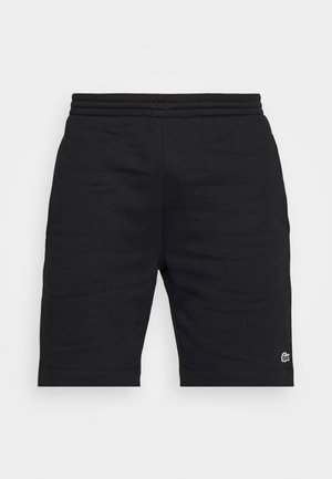 Short noir longueur genou avec taille élastique et petit logo crocodile vert sur la partie inférieure de la jambe gauche.