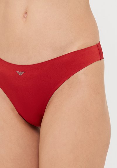Slip inferior roșu dintr-un material neted. Are o croială jos, cu o acoperire minimă și un mic accent metalic cu logo în apropierea taliei.