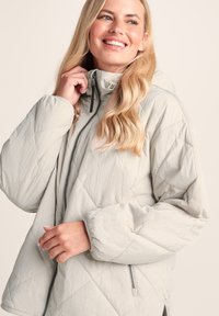 Light grey quilted jacket with a high collar, zip front, and elastic cuffs, featuring a soft texture and geometric diamond pattern.