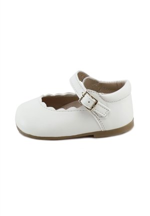 Zapato Mary Jane blanco para niño pequeño con borde festoneado, correa ajustable, hebilla dorada y suela marrón, mostrado de lado sobre un fondo blanco.