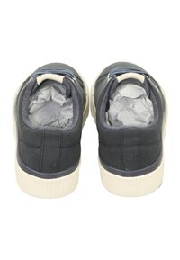Dark blue fabric shoes with cream rubber soles, featuring a rounded toe and padded collars, displaying crumpled paper inside.