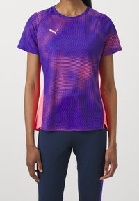 Camiseta deportiva morada con acentos rosas, que presenta un patrón texturizado, mangas cortas y un escote redondeado. Tejido ligero.