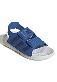 Modra športna sandal z nastavljivimi Velcro trakovi, kontrastnim belim podplatom, teksturirano notranjostjo in subtilnim logotipom. Lahka in oblazinjena zasnova.