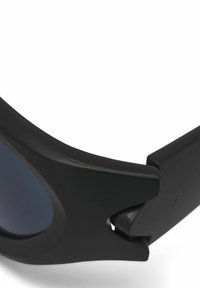 Schwarze Sonnenbrille mit matter Oberfläche, gekrümmtem Rahmen, dunklen Gläsern und einem einzigartigen Ausschnitt-Design an den Schläfen.