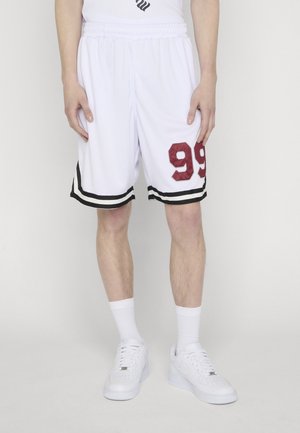 Shorts atletici bianchi con strisce nere all'orlo e numero "99" color bordeaux sulla coscia destra, indossati con calzini bianchi e scarpe da ginnastica bianche su una persona in piedi.