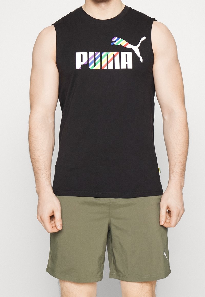 Débardeur noir sans manches arborant le logo "PUMA" multicolore et un graphisme stylisé de puma. Associé à un short kaki.