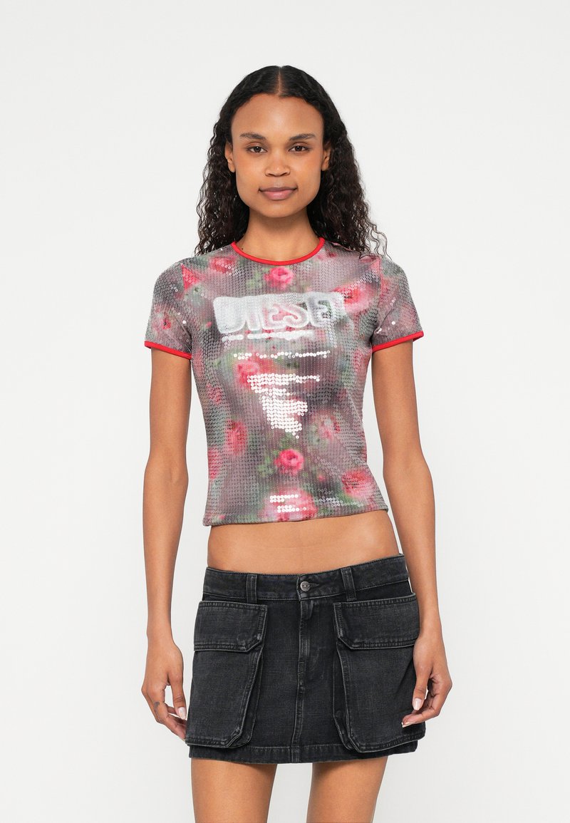 Tričko s krátkym rukávom zdobené flitrami s kvetinovým vzorom v odtieňoch ružovej, s okrúhlym výstrihom a červeným lemom. Nosené s čiernou džínovou sukňou.