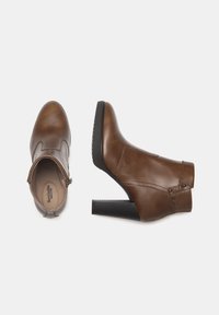 Brown leather ankle boots with a rounded toe, a block heel, zipper closure, and decorative studs on the side. Textured black sole.
