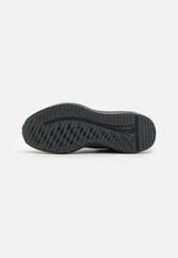 Suela de zapatilla negra con un patrón de tracción de goma texturizada, que presenta surcos y aristas distintivas para un mejor agarre. Diseño sólido, con minimalismo en sus adornos.