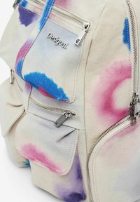 Baumwoll-Rucksack mit rosa, blauen und lila Batiktmustern, ausgestattet mit silbernen Reißverschlüssen und mehreren Fronttaschen für Stauraum.