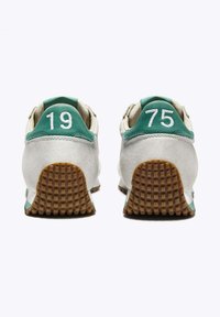 Scarpe sportive con tomaia in suede grigia, dettagli verdi e numeri ricamati bianchi "19" e "75" sui talloni. Suola in gomma testurizzata.
