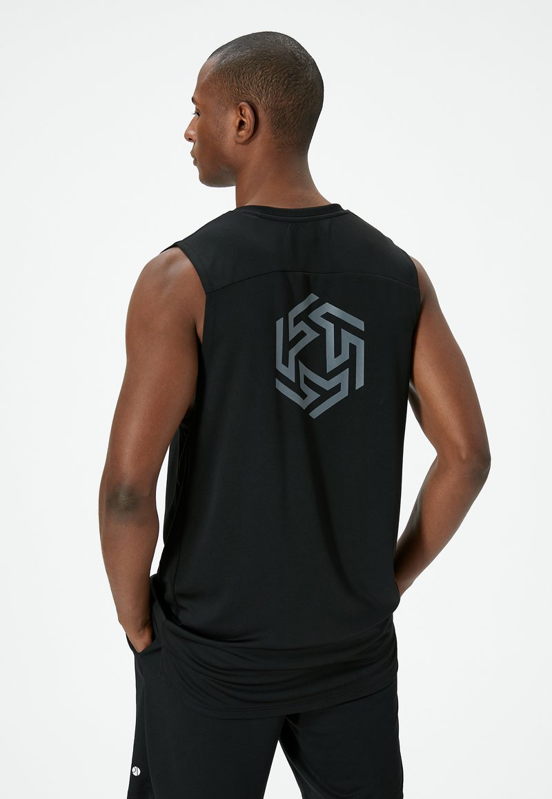 Svart ärmlös sporttop i lätt tyg, med en geometrisk logotyp i grått på baksidan. Slät textur, avslappnad passform.