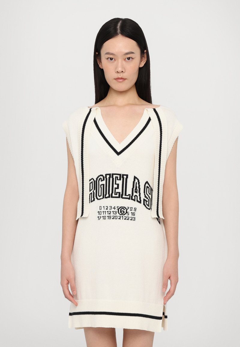 Knit dress in cream with black accents, featuring a V-neck, short sleeves, and printed text and numbers in the center. Soft texture.