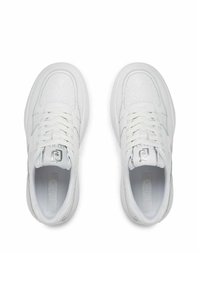 Scarpe da ginnastica bianche con una tomaia testurizzata, dotate di lacci piatti, suola robusta e un branding discreto sulla linguetta.