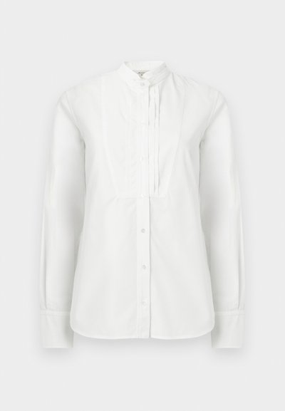 Biela košeľa s dlhým rukávom vyrobená z bavlny, s vysokým golierom, predným zapínaním na gombíky a vertikálnymi záhybmi pozdĺž stredu.