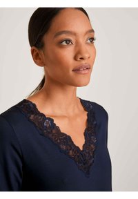 Top navy con scollatura a V decorato con un intricato bordo in pizzo nero. Tessuto morbido con una silhouette aderente.