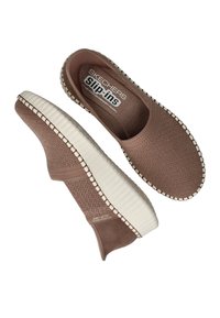 Skechers slip-on shoes, beige textured fabric upper, white rubber sole with stitched accents, cushioned insole labeled "Air Cooled Memory Foam."