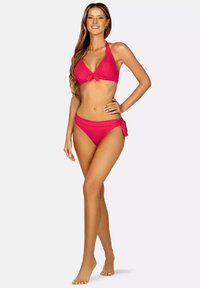 Różowy bikini w prążki, składający się z topu na halter z węzełkiem z przodu oraz wysokich majtek z wiązaniami po bokach. Gładka faktura i żywy kolor.