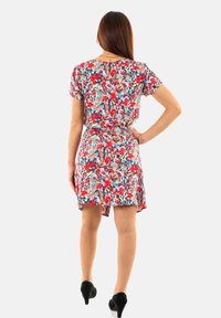 Vestido de manga corta, hasta la rodilla, con un vibrante estampado floral en rojo, rosa y turquesa sobre un fondo blanco; ceñido en la cintura.