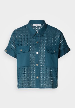Blouse à manches courtes teal avec des détails en dentelle et deux poches poitrine. Présente un devant boutonné et un col. Texturé avec des motifs ajourés.