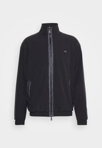 Svart zip-up träningsjacka med ståkrage, resårmanchetter och nederkant, sidofickor med dragkedja och subtil Adidas-logga på bröstet.