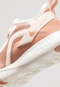 Nike Flex-sneakers met een mesh bovenwerk in lichtroze en beige, voorzien van een opvallend logo, een gestructureerd ontwerp en een witte zool.