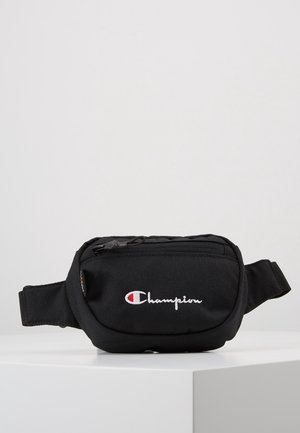 Black fabric Champion waist bag with zippered main pocket and branded logo on front, placed on a white surface.